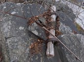 Løypestrengfestet nede. Strengen er kveila på ein rull av tre som er plassert i to jernbøylar festa i ein svær stein.