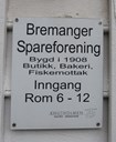 Skilt ved inngangsdør på overnattingsstaden Bremanger Spareforening. Overnattingsstaden har teke med historie frå den tidlegare landhandelen Bremanger Spareforening; namnet, byggjeår og kva BS var for slags verksemd.
