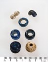 Ymse perler frå Ytre Moa, mellom anna ei blå og kvit såkalla dobbeltperle, samt enkle blå glasperler. Denne typen perler har ei generell datering til yngre jarnalder (Foto: Fylkesarkivet).