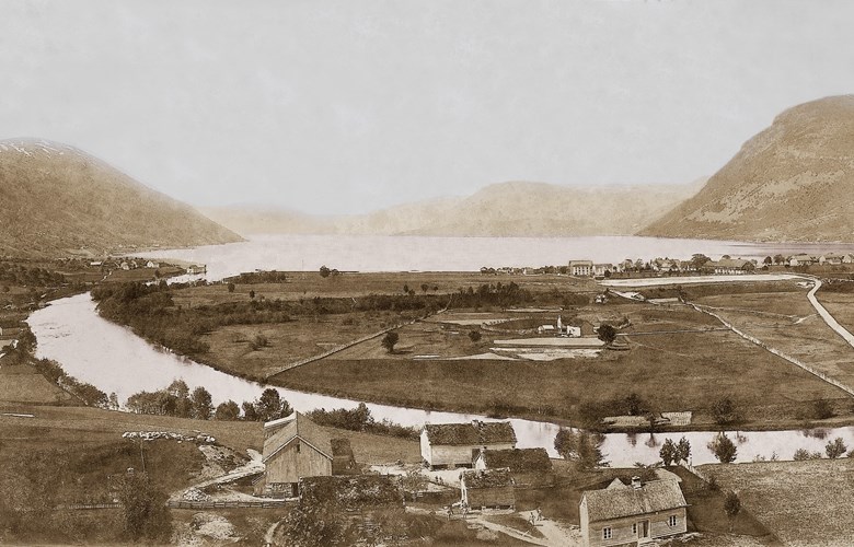 Bilde er tatt frå Stovehogjen på Skipenes ca. 1895. Det viser eksersisplassen ved elva ned mot fjorden.