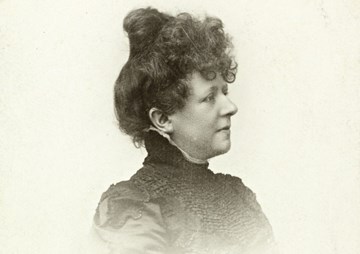Portrettfoto av ei dame med oppsatt hår. Ho ser til sida og ein kan berre sjå halve ansiktet
