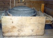 Oversteinen med <em>auga </em> (opning) for korn (rett over), <em>ringar</em> ved sida av steinane som samlar opp mjølet og <em>grøttet</em> (kassen framfor det mjølet samlar seg).