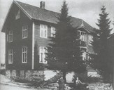 Bygningen som Henrik Gundersen kjøpte og nytta som hotell. Huset vart rive kring 1970 i samband med omregulering av Naustdal sentrum. Framfor bygningen står Gunnhild Gundersen og mannen hennar, Albert Henriksen. Gunnhild og Albert dreiv hotellet ei tid. Ho var postopnar i Naustdal i perioden 1921-1947.
