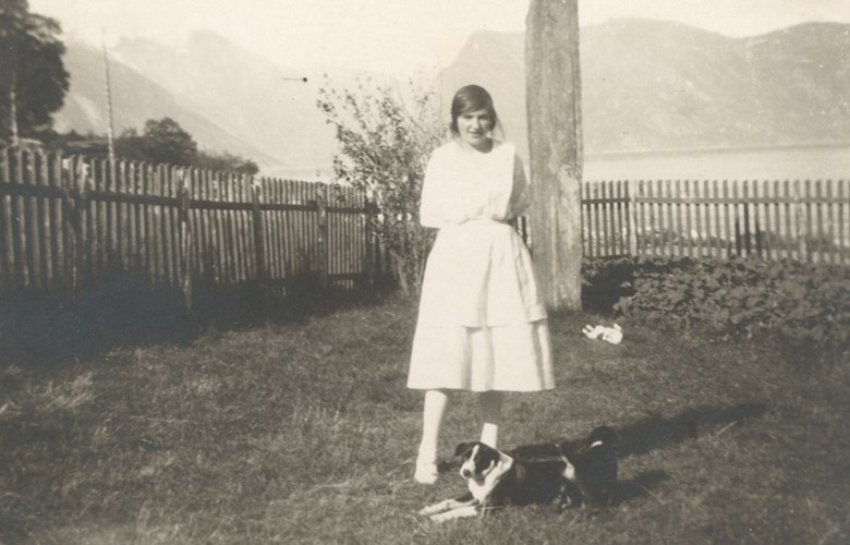 Margit Hovland, fødd 1907, dotter til handelsmann Hjalmar Hovland framfor 1905-steinen i hagen deira.
