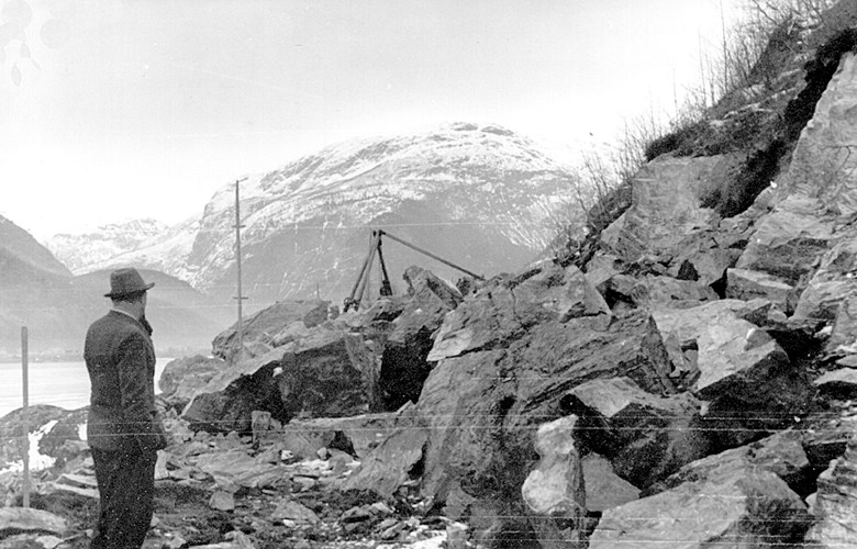 Ein tysk ingeniør på synfaring 19. mars 1941. Steinbukkar eller stubbebrytar vart nytta til opplasting av stein og til muring. Vegen var farbar ved årsskiftet 1941-42. Øvre Årdal i bakgrunnen.