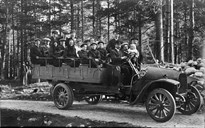 Her er folk frå Sandane på tur til Breim i 1913 med den første rutebilen som gjekk mellom Vadheim og Sandane. Bilen tilhøyrde A/A Fjordenes Automobilselskap, som var skipa same året. Kommunestyret meinte at køyringa på den einaste hovudvegen i kommunen, Sandane-Reed, var svært farleg. 