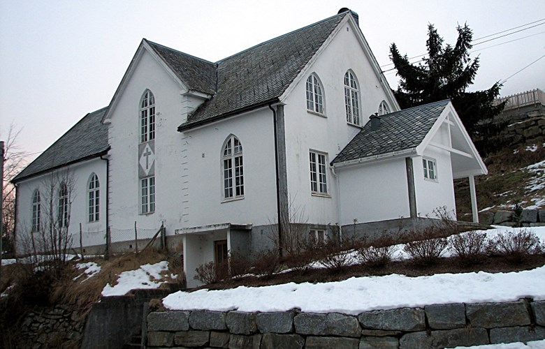 Samlingsheimen på Stårheim. Huset ligg tett attmed kyrkja på vestsida av elva. 