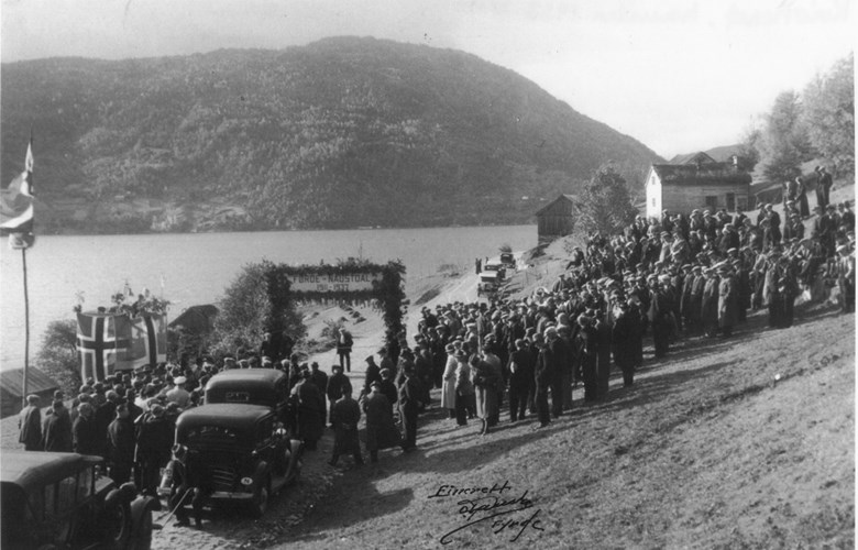 Frå opninga av vegen Førde-Naustdal, 9. oktober 1937. 600 personar var tilstades. Det var reist æresport og pynta med grønt og flagg.  Førde hornmusikk deltok. Etter opninga gjekk det bilkortesje frå Klopstad til Fimland i Naustdalen.