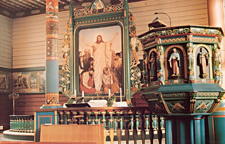 Frå interiøret i Eid kyrkje med litt av Lars. T. Kinsarvik sine dekorasjonar. Både i taket, på veggene, ramma til altertavla, søylene, alterringen og preikestolen er den særmerkte stilen til Kinsarvik tydeleg.
