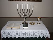 Altarbordet med liturgibok, salmebok, sjuarma lysestake, oblatøskje og kalk.



