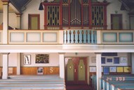 Biletet syner delar av skipet, inngangsdøra og galleriet med orgelet.