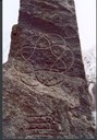 Solkors-symbolet står på framsida (austsida) av steinen, kranssymbolet på baksida.