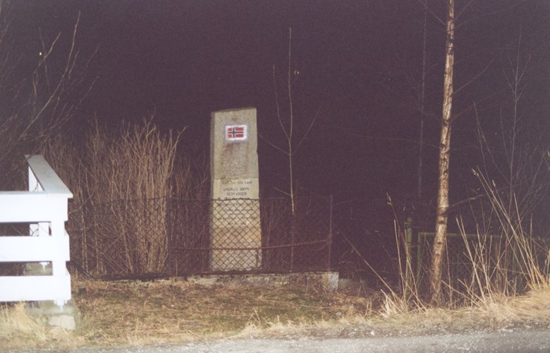 Minnesteinen over Andrias Bryn står på austsida av vegen i tettstaden i Gudvangen. Han er innhegna med eit flettverksgjerde.