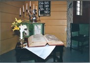 Christian IIIs bibel vart prenta i København i 1550. Dette var den fyrste trykte bibelutgåva i Norge. Dåpsmugga i sølv er truleg frå 1944. I bakgrunnen ser vi også ein sjuarma lysestake og den gamle salmenummertavla.