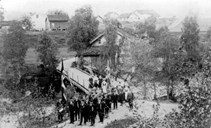 Biletet viser den gamle Rødemels bro, truleg 17. mai 1913. Fotografen har stått på nordsida av elva og teke biletet mot Tomasgard.