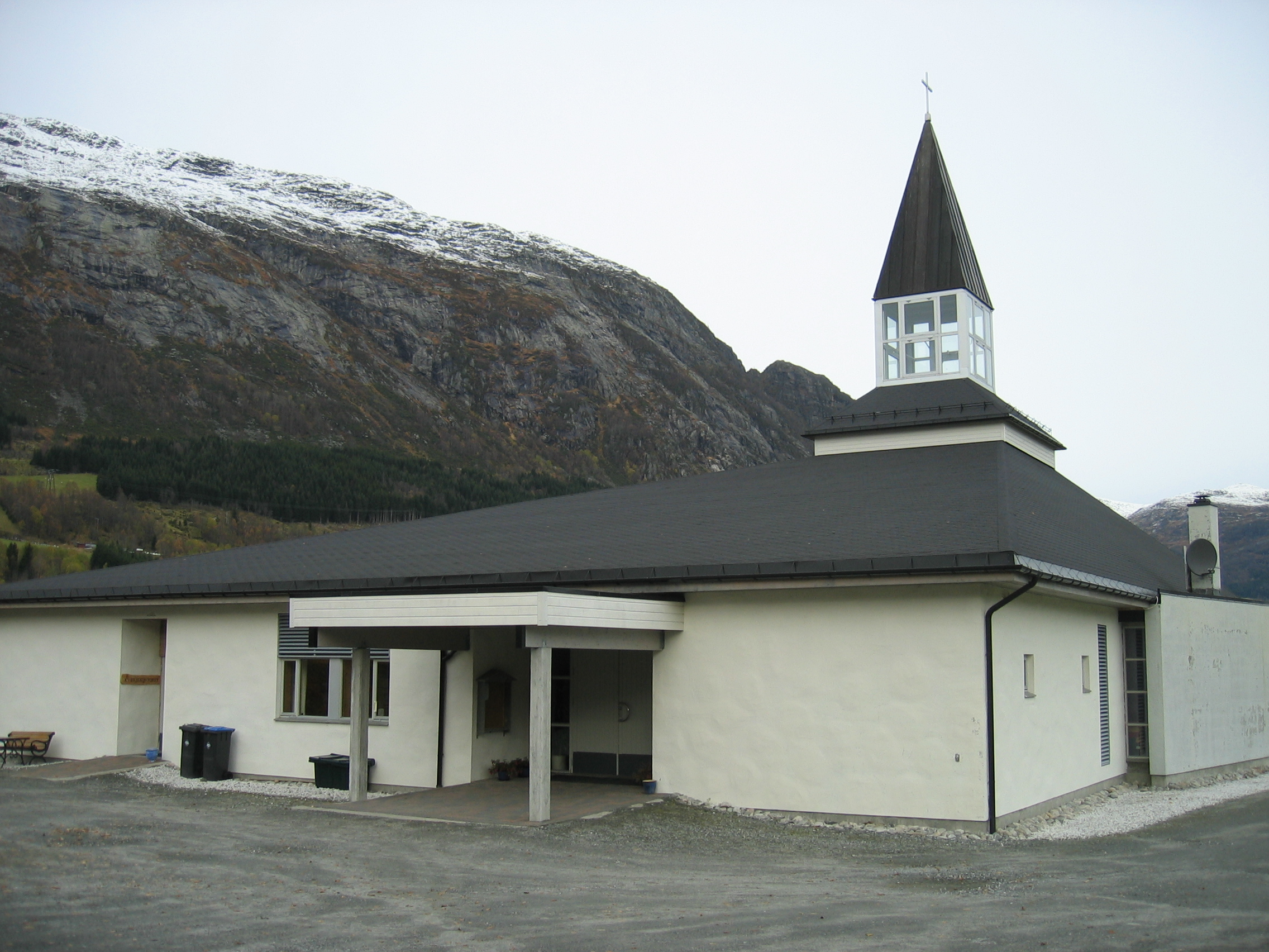 Kyrkja er bygd i lecastein som er kvitmåla. Taket er forma som ein skeiv pyramide med eit tårn over austenden.