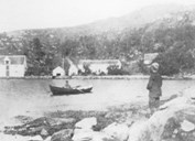 Bryggja slik staden såg ut før brannen i 1898. Mannen i robåten og guten på stranda veit me ikkje namna på.