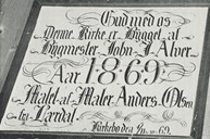 Skiltet fortel at kyrkja vart reist av byggmeister John J. Alver i 1869, og at ho er måla av Anders Olsen (Storemaolaren) frå Lærdal. Olsen måla også altertavla, og truleg dette skiltet.